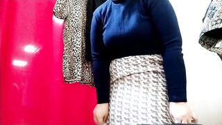 Curvy lady with a big butt tries on clothes in a shopping mall fitting room