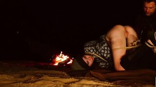 Horny bound BDSM lover in night time anal pleasure scene by the crackling fire pit for sub beauty